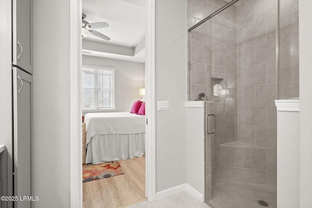 full bathroom featuring wood finished floors, a shower stall, ensuite bathroom, baseboards, and a ceiling fan