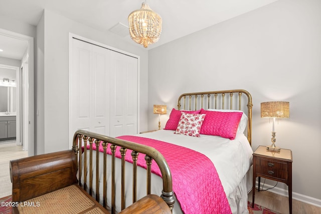 bedroom featuring wood finished floors, baseboards, a notable chandelier, and a closet