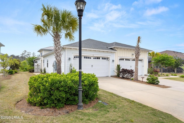 view of side of home with driveway, board and batten siding, a lawn, and an attached garage