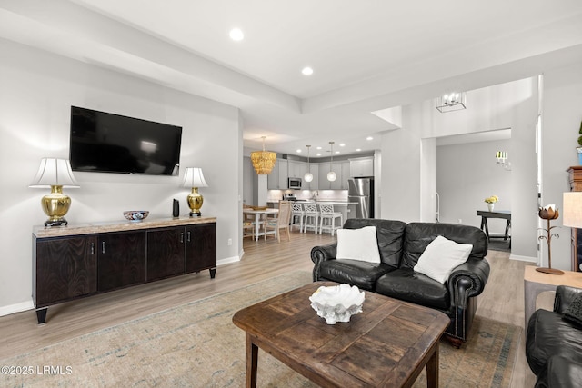 living area with light wood finished floors, recessed lighting, a notable chandelier, and baseboards
