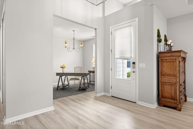 foyer entrance featuring baseboards, a chandelier, and light wood-style floors