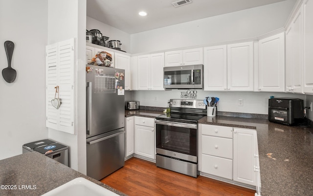 kitchen with dark wood-type flooring, stainless steel appliances, and white cabinets