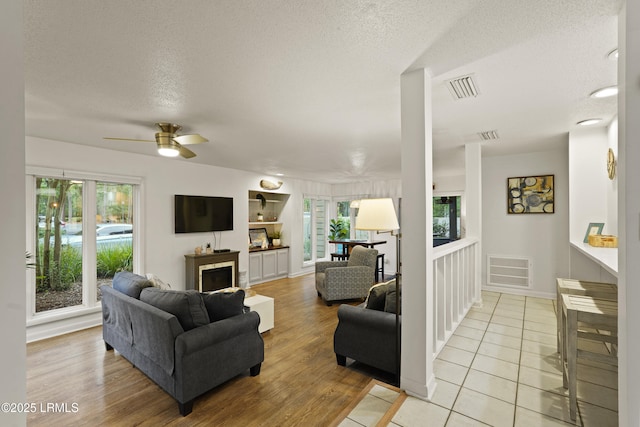 20 Queens Folly Rd Unit 1967, Hilton Head Island, SC 29928 - living room with ceiling fan, healthy amount of natural light, a fireplace, a textured ceiling, and light wood-type flooring