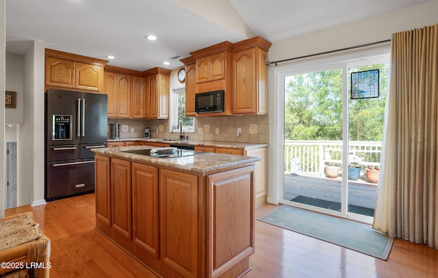 3 Ocean Marsh Ln, Harbor Island, SC 29920 - kitchen featuring black appliances, light wood-style floors, a kitchen island, decorative backsplash, and light stone countertops