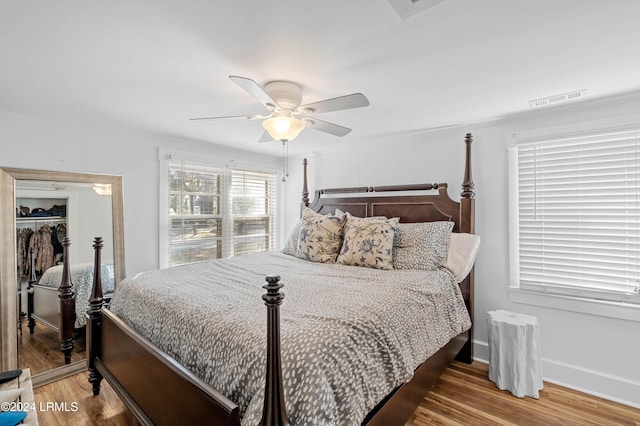 bedroom with ceiling fan, wood-type flooring, a spacious closet, and a closet