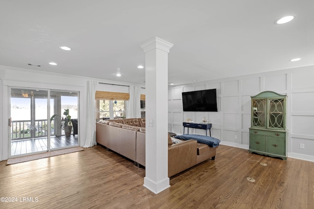 unfurnished living room with hardwood / wood-style flooring, ornamental molding, and ornate columns