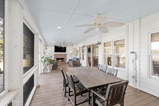 sunroom with ceiling fan, plenty of natural light, and a brick fireplace