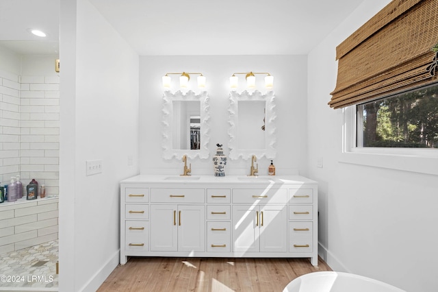 bathroom with hardwood / wood-style floors, vanity, and a tile shower