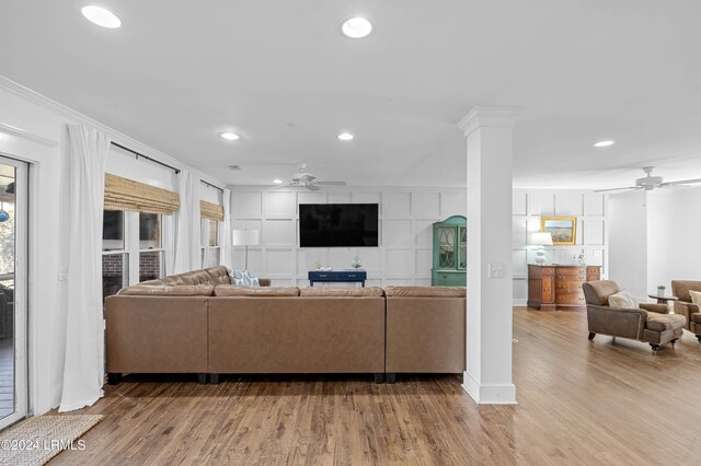 living room with decorative columns, ornamental molding, ceiling fan, and light hardwood / wood-style flooring