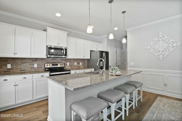 kitchen with crown molding, a sink, wood finished floors, appliances with stainless steel finishes, and white cabinets