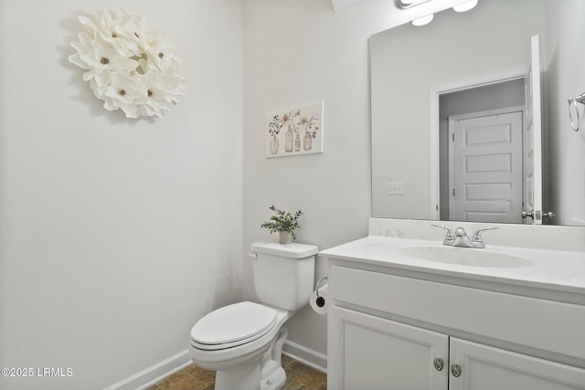 half bath featuring baseboards, toilet, and vanity