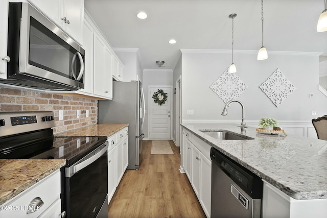 kitchen with white cabinets, a sink, crown molding, and appliances with stainless steel finishes