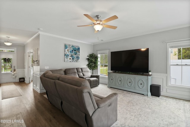 living area with a wainscoted wall, wood finished floors, crown molding, and ceiling fan