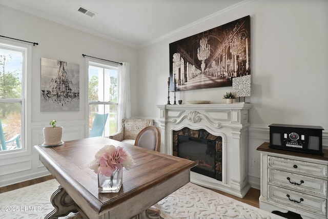 interior space with visible vents, ornamental molding, a fireplace, and wood finished floors
