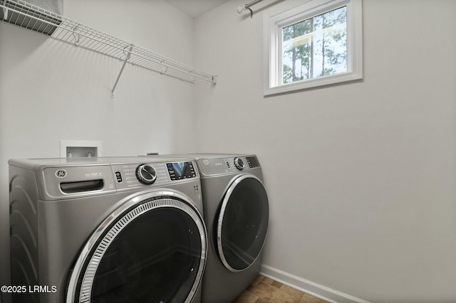 laundry room with washer and clothes dryer, stone finish flooring, baseboards, and laundry area