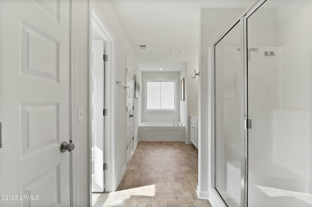 bathroom featuring a bath, visible vents, a shower stall, stone finish flooring, and baseboards