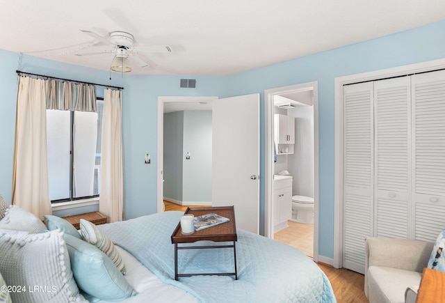 bedroom featuring ensuite bath, light hardwood / wood-style flooring, ceiling fan, and a closet