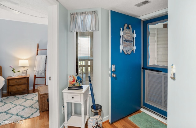 doorway with a textured ceiling and light hardwood / wood-style flooring