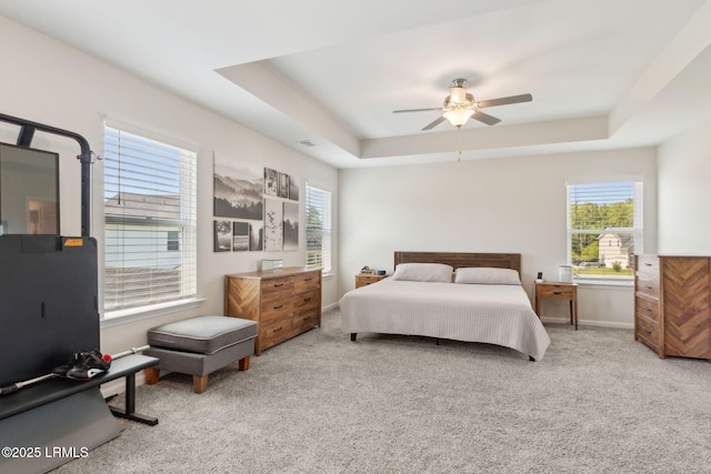 bedroom featuring a raised ceiling, carpet flooring, a ceiling fan, and baseboards