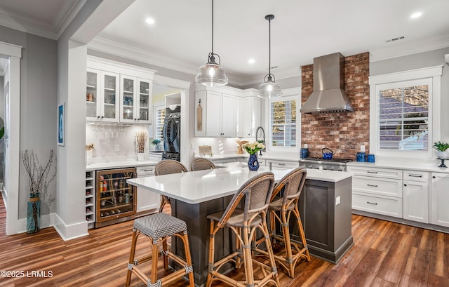 kitchen featuring wall chimney range hood, a center island, and white cabinets