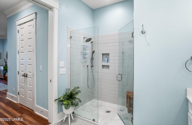 bathroom featuring ornamental molding, a shower with shower door, hardwood / wood-style floors, and vanity