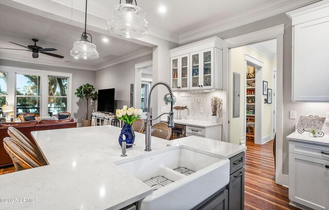 kitchen with pendant lighting, sink, white cabinetry, dark hardwood / wood-style floors, and ornamental molding