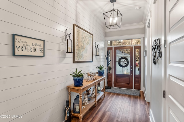 interior space with crown molding, a notable chandelier, dark hardwood / wood-style flooring, and wood walls