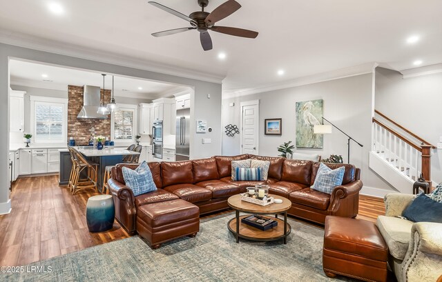 living room with crown molding, wood-type flooring, and ceiling fan