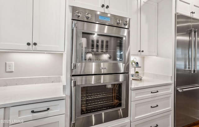 kitchen featuring light stone counters, appliances with stainless steel finishes, and white cabinets