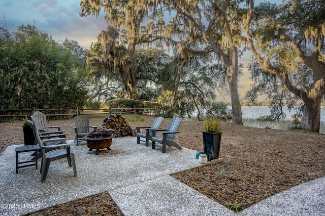 patio terrace at dusk with a fire pit and a water view