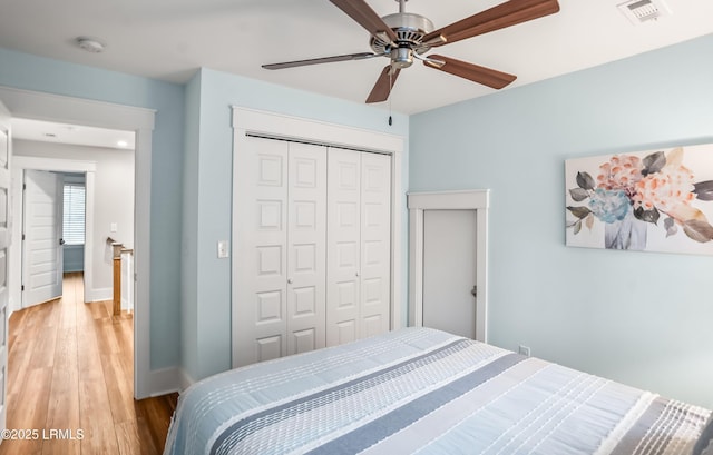 bedroom with light hardwood / wood-style floors, ceiling fan, and a closet