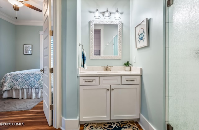 bathroom featuring hardwood / wood-style floors, ornamental molding, vanity, ceiling fan, and walk in shower