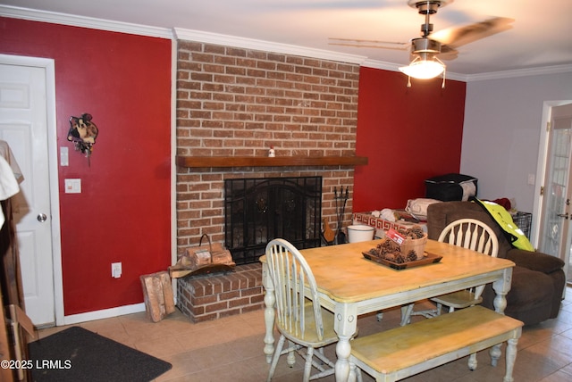 tiled dining area featuring crown molding, ceiling fan, and a fireplace