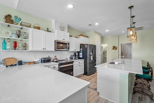 kitchen with decorative light fixtures, tasteful backsplash, sink, stainless steel appliances, and light hardwood / wood-style flooring