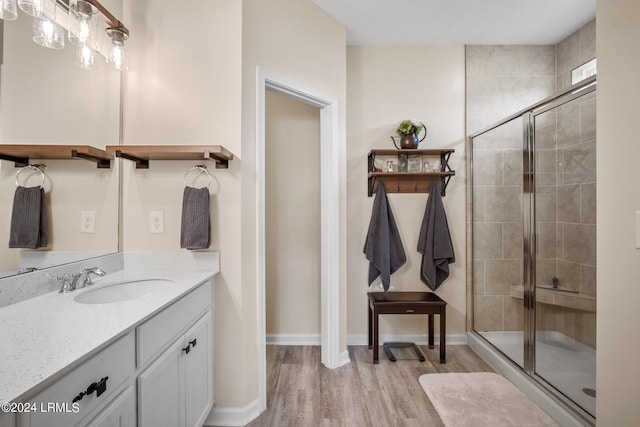 full bath with wood finished floors, a shower stall, vanity, and baseboards