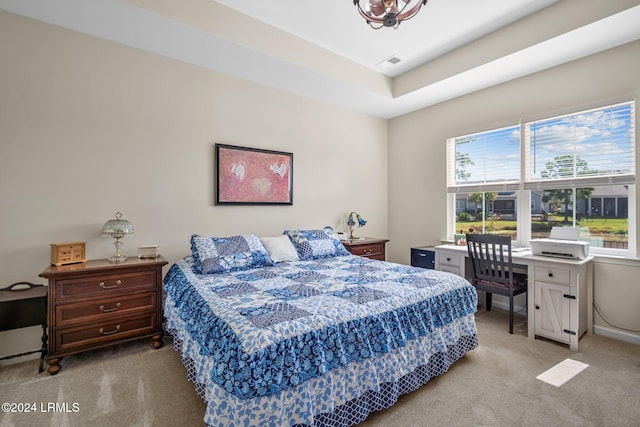 bedroom with a tray ceiling, light carpet, and visible vents