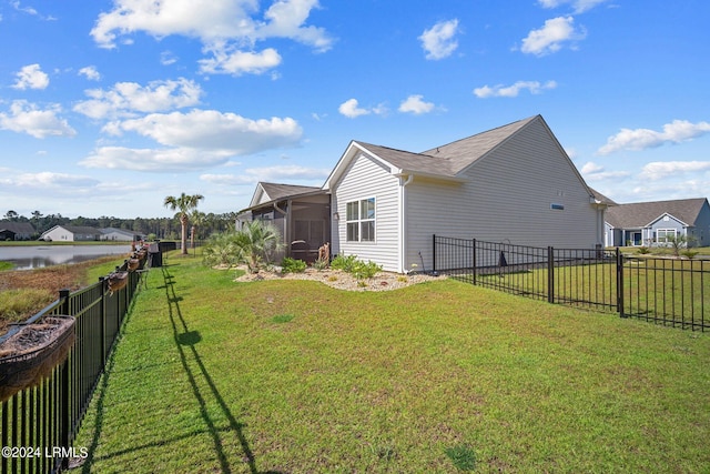 view of home's exterior featuring a water view, a yard, and a sunroom