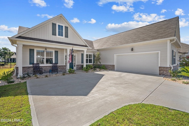 view of front of property featuring brick siding, covered porch, board and batten siding, a garage, and driveway