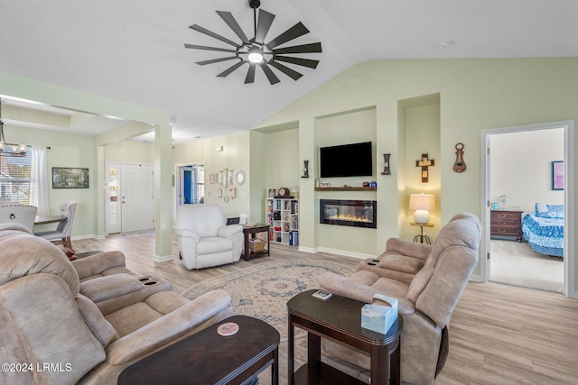 living area with a chandelier, baseboards, vaulted ceiling, light wood-style floors, and a glass covered fireplace