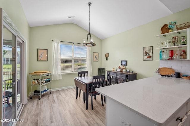 dining space featuring light wood-style flooring, visible vents, baseboards, vaulted ceiling, and an inviting chandelier