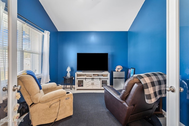 living room featuring lofted ceiling, carpet flooring, and baseboards