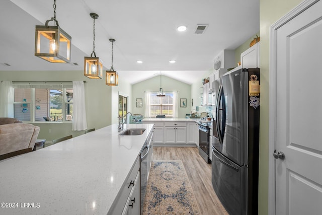 kitchen featuring visible vents, white cabinets, lofted ceiling, appliances with stainless steel finishes, and a sink