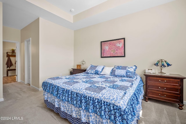 bedroom with light colored carpet and a tray ceiling