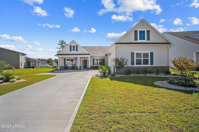 view of front of house with board and batten siding, a front yard, brick siding, and driveway