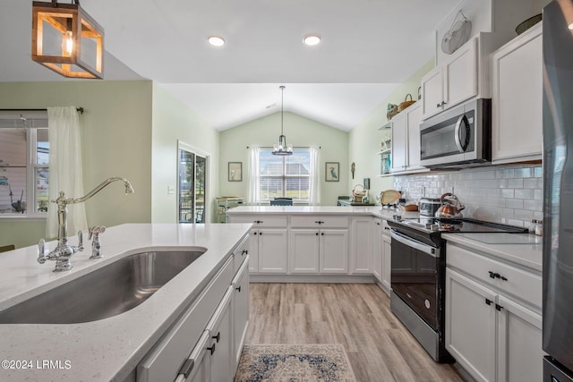 kitchen featuring pendant lighting, sink, lofted ceiling, appliances with stainless steel finishes, and white cabinets