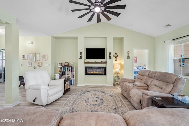 living room with lofted ceiling, visible vents, a ceiling fan, light wood-type flooring, and a glass covered fireplace