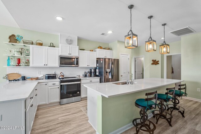 kitchen featuring decorative light fixtures, sink, white cabinets, decorative backsplash, and stainless steel appliances