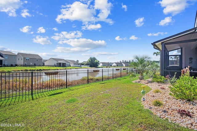 view of yard featuring a residential view, a water view, and fence