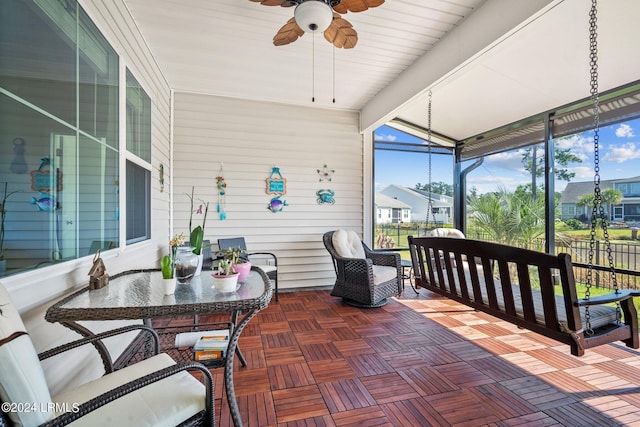 sunroom featuring lofted ceiling with beams and a ceiling fan