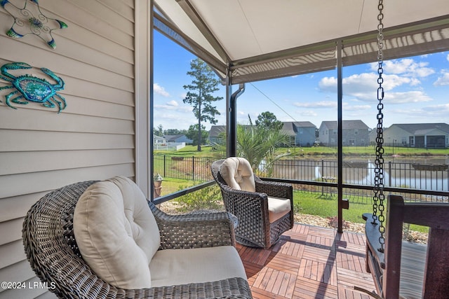 sunroom with a water view, a residential view, and vaulted ceiling